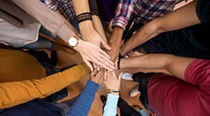 Ehrenamt - Das Bild zeigt viele aufeinander gelegte Hände. Die Hände stehen für Zusammenhalt.